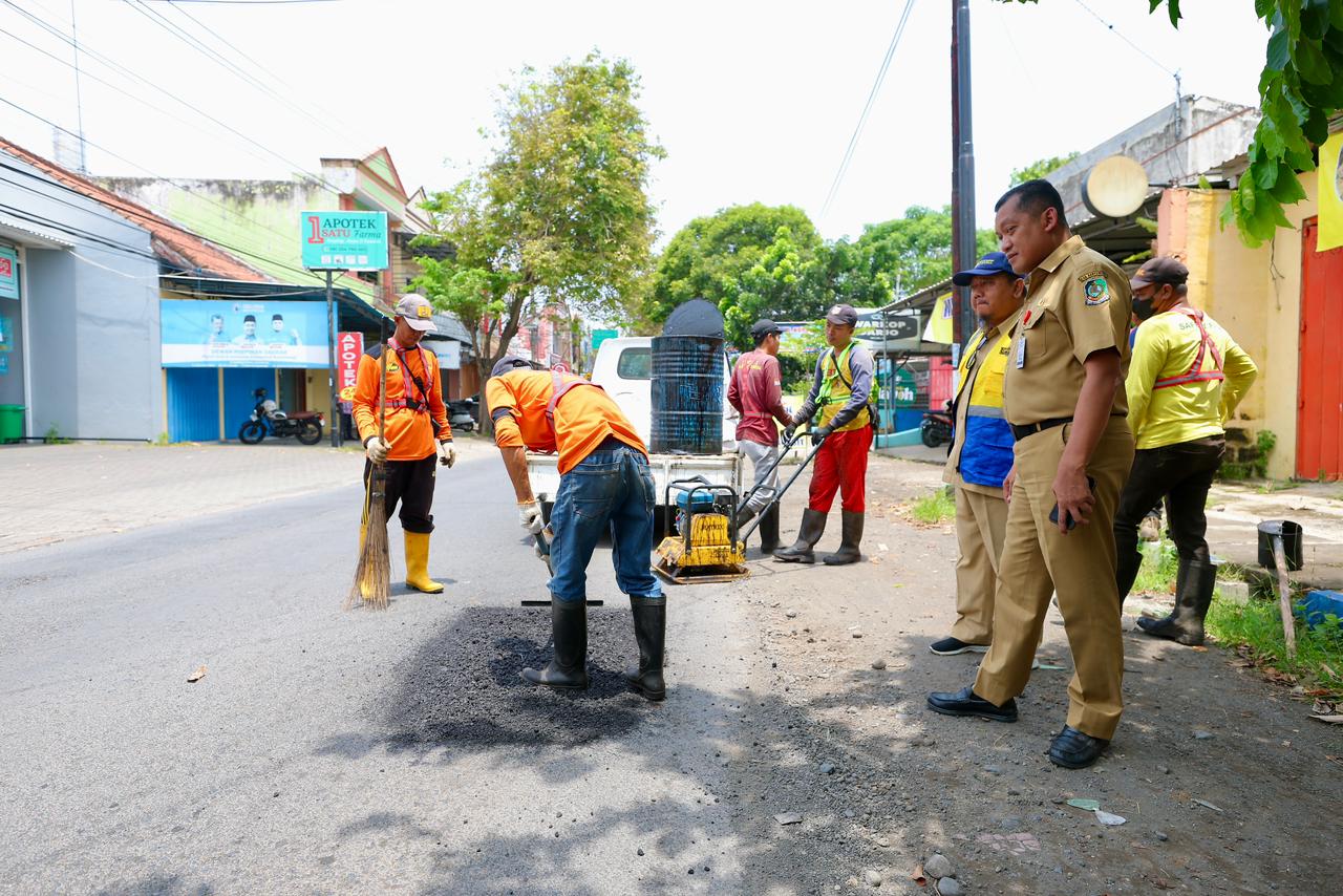 Petugas Satgas Jalan Berlubang Banyuwangi menambal jalan rusak menggunakan hotmix di salah satu ruas jalan kota.