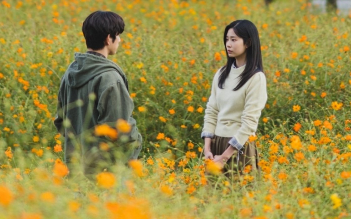 Adegan Yeon Tae Seo dan Mo Eun Ah duduk berdampingan di ladang bunga kuning dalam drama Still Shining