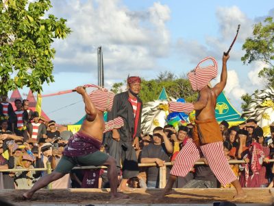 Dua pria bertelanjang dada sedang bertanding Ojung dengan rotan di arena Pantai Galung, Sumenep, disaksikan ribuan penonton/Foto: Humas Pemkab Sumenep