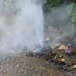 Semburan air panas setinggi tiga meter dari geyser di Pemandian Cipanas Cisolok, Pelabuhan Ratu, dengan latar belakang pepohonan hijau dan kabut tipis.