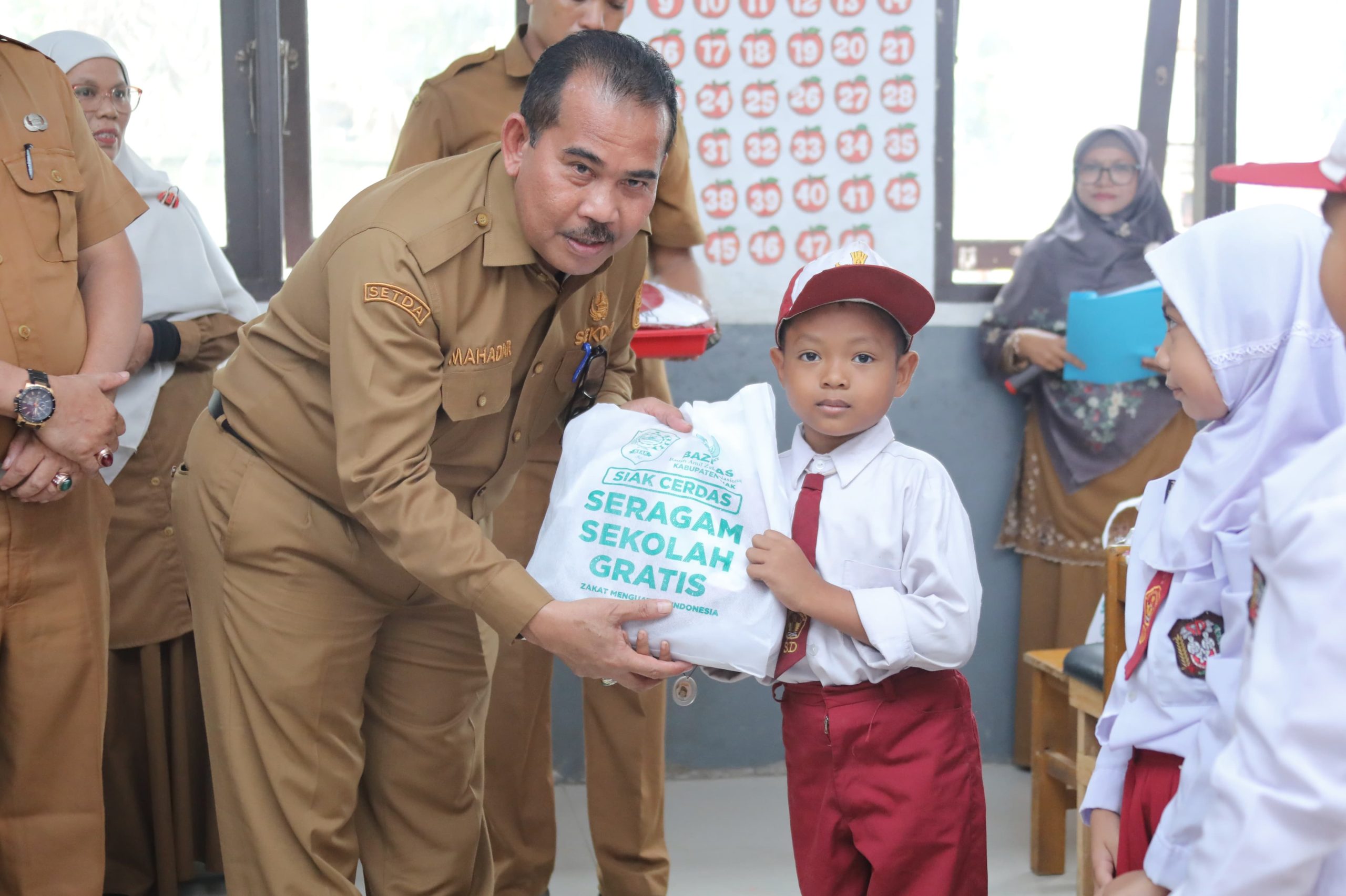 Sekda Siak Mahadar menyerahkan bantuan seragam sekolah gratis kepada siswa baru di SD Negeri 14 Teluk Mesjid/Foto: Media Center Siak