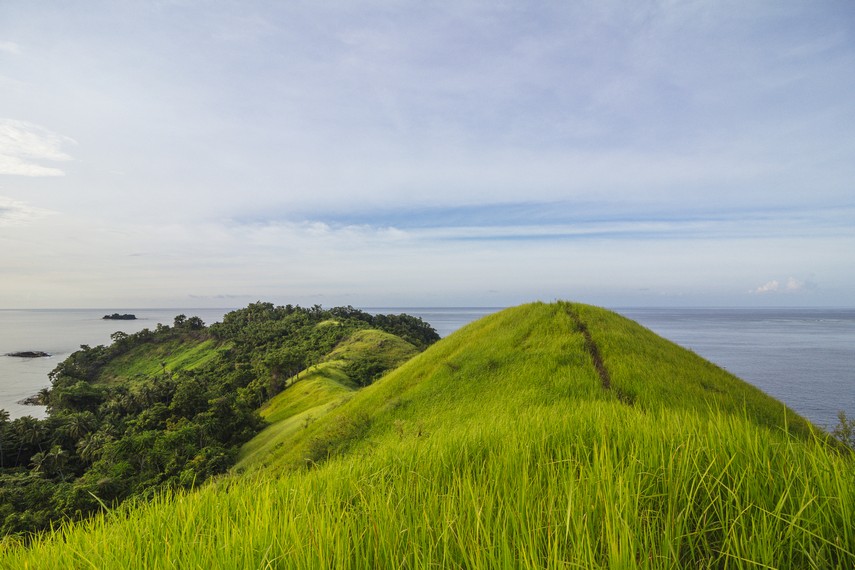 Pulau Diyonumo di Gorontalo Utara menyuguhkan hamparan rumput hijau di puncak bukit. Pulau perawan tanpa fasilitas wisata ini bisa dicapai dengan kapal nelayan/Foto: Indonesia Kaya